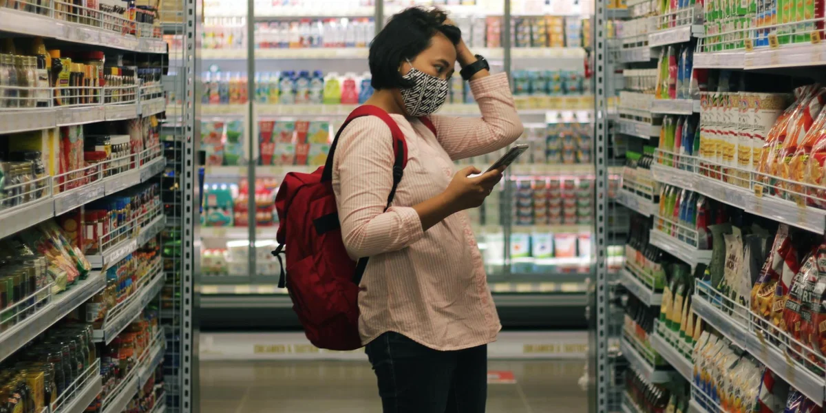 Standing woman looking at grocery store aisle with hand in hair